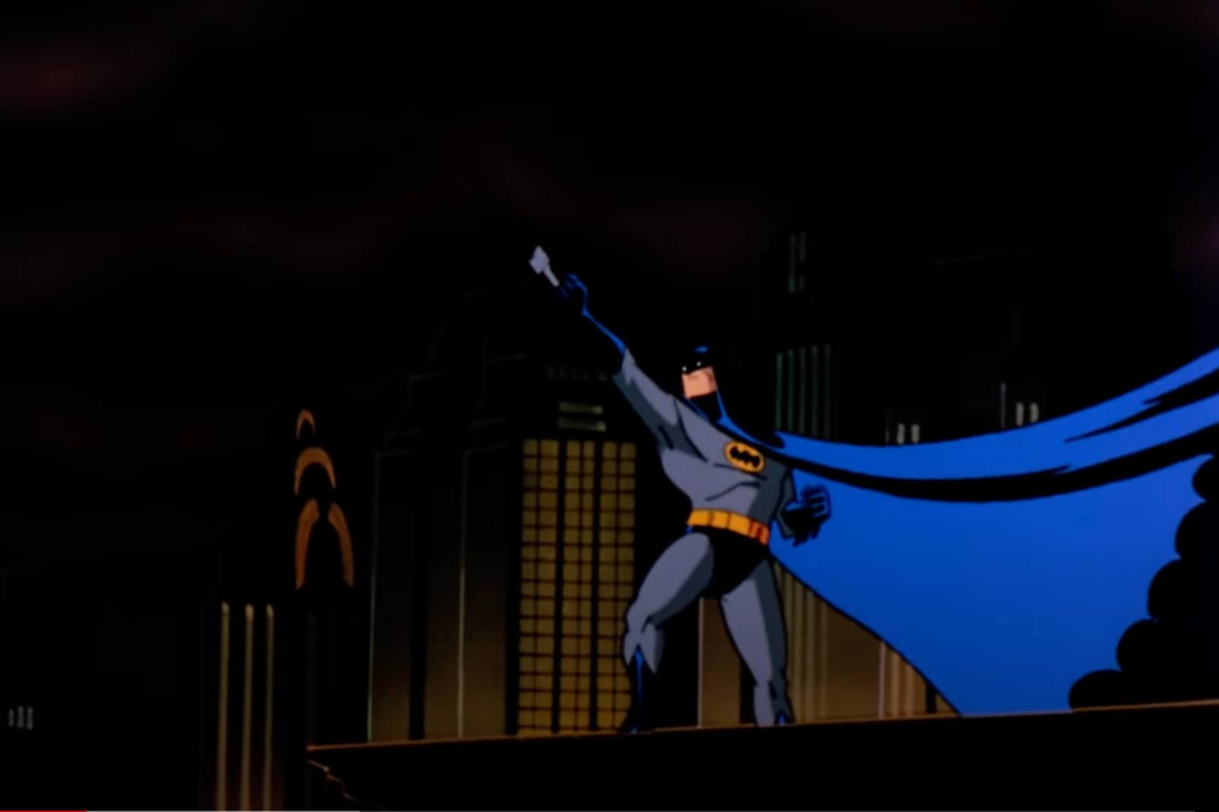 animated Batman standing on a rooftop with a dark city skyline in the background. He is holding a Batarang, ready to throw, and his blue cape billows dramatically. Iconic buildings, including one resembling the Chrysler Building, are visible.
